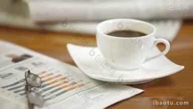 一个男人在读报纸，伸手去拿他的早餐咖啡
